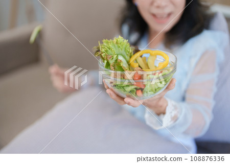 Portrait of an elderly Asian woman taking care of her health by eating salad 108876336