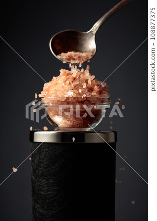 Pink salt is poured into a small bowl. Pink salt is poured into a small bowl. 108877375