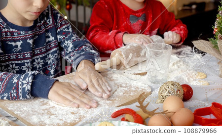 Closeup of child's hands rolling dough for Christmas cookies for Santa on kitchen table Closeup of child's hands rolling dough for Christmas cookies for Santa on kitchen table 108879966