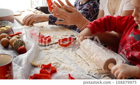Closeup of family hands rolling dough and cutting cookies and ginger bread for Christmas celebrations. Winter holidays, celebrations and party. Closeup of family hands rolling dough and cutting cookies and ginger bread for Christmas celebrations. Winter holidays, celebrations and party. 108879975