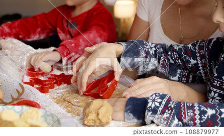 Closeup of little boys rolling dough and making cookies for Santa with mother on kitchen. Winter holidays, celebrations and party. Closeup of little boys rolling dough and making cookies for Santa with mother on kitchen. Winter holidays, celebrations and party. 108879977