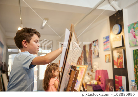 Lifestyle portrait of adorable talented kids learning drawing on canvas in a modern creative fine art studio Lifestyle portrait of adorable talented kids learning drawing on canvas in a modern creative fine art studio 108880990