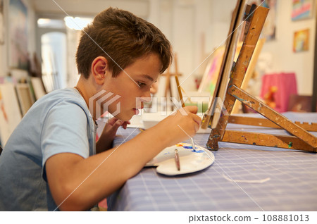 Handsome teenage, schoolboy artist painting on canvas, drawing with inspiration in creative fine art studio. Handsome teenage, schoolboy artist painting on canvas, drawing with inspiration in creative fine art studio. 108881013