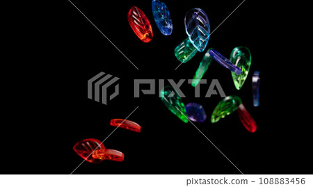 Fashion colorful plastic leaf with beautiful work detail is value. Luxury leaf bead red blue green is fashion trend and fly in air. Black background isolated selective focus blur Fashion colorful plastic leaf with beautiful work detail is value. Luxury leaf bead red blue green is fashion trend and fly in air. Black background isolated selective focus blur 108883456
