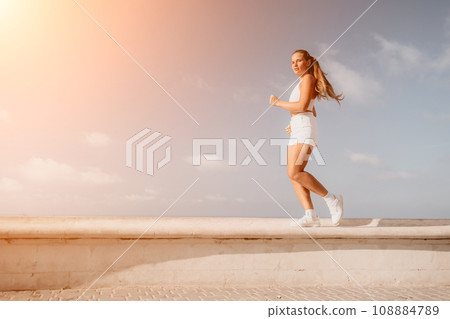 Fitness woman sea. Active, happy middle-aged woman in white sportswear exercises outdoors in a park over sea. Healthy lifestyle, physical activity and female fitness pilates and yoga routines. Fitness woman sea. Active, happy middle-aged woman in white sportswear exercises outdoors in a park over sea. Healthy lifestyle, physical activity and female fitness pilates and yoga routines. 108884789