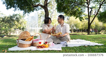 Cheerful elderly couple asian wear casual clothes sitting in the park having a party together 108887376