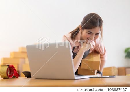 Asian woman entrepreneur prepare parcel box and check online order on laptop computer for commercial checking delivery. online marketing, packing box, SME seller. startup business concept Asian woman entrepreneur prepare parcel box and check online order on laptop computer for commercial checking delivery. online marketing, packing box, SME seller. startup business concept 108887437
