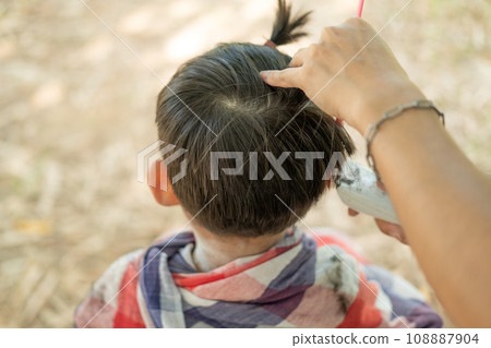 Barber cutting hair of an Asian boy In an open space filled with trees. Barber cutting hair of an Asian boy In an open space filled with trees. 108887904