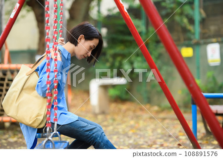 A woman killing time in the park 108891576