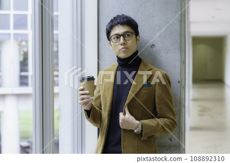 Portrait of a young man wearing glasses and standing with a drink cup Photography cooperation: Ariake College of Education and Art 108892310