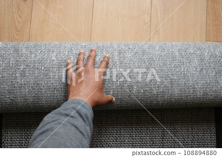 top view of men rolling out new rug. 108894880