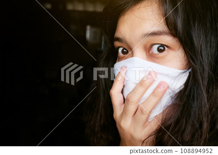 Asian Thai woman wearing a white cloth mask for prevent the Covid-19 or Corona virus in Thailand. She is serious and Coughing about Air Pollution Value Pm 2.5. Health and Respiratory system concept 108894952