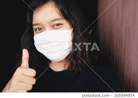 Asian Thai woman wearing a white cloth mask for prevent the Covid-19 or Corona virus in Thailand and Thumbs up and smiling for protection in Air Pollution Value Pm 2.5. Health and medical concept Asian Thai woman wearing a white cloth mask for prevent the Covid-19 or Corona virus in Thailand and Thumbs up and smiling for protection in Air Pollution Value Pm 2.5. Health and medical concept 108894954