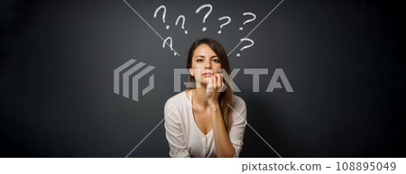Young woman with question mark on gray background. minded woman touch hand chin. think thoughts about life problems. isolated over dark gray background 108895049