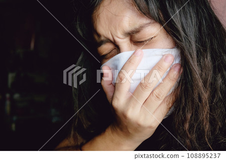 Asian Thai woman wearing a white cloth mask for prevent the Covid-19 or Corona virus in Thailand. She is serious and Coughing about Air Pollution Value Pm 2.5. Health and Respiratory system concept Asian Thai woman wearing a white cloth mask for prevent the Covid-19 or Corona virus in Thailand. She is serious and Coughing about Air Pollution Value Pm 2.5. Health and Respiratory system concept 108895237
