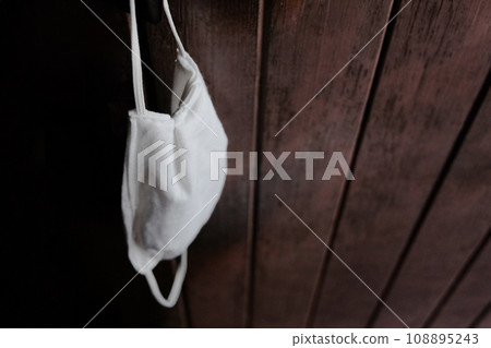 A white cloth mask for prevent the Covid-19 or Corona virus and protect for Air Pollution Value Pm 2.5 hanging on wooden doors. Health and Disease Concept A white cloth mask for prevent the Covid-19 or Corona virus and protect for Air Pollution Value Pm 2.5 hanging on wooden doors. Health and Disease Concept 108895243