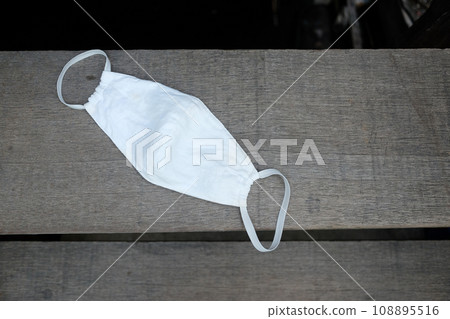 White cloth mask for prevent the Covid-19 or Corona virus is littering on wooden stairs White cloth mask for prevent the Covid-19 or Corona virus is littering on wooden stairs 108895516