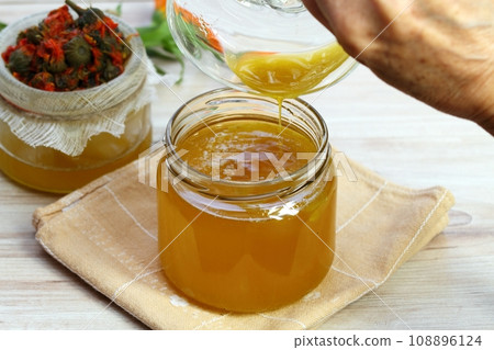 Pouring melted natural beeswax into warm herbal ointment 108896124