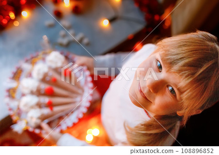 Little preschool girl holding reindeer made with chocolate cocoa powder and marshmallows. Selfmade dessert drink for children on Christmas. Little preschool girl holding reindeer made with chocolate cocoa powder and marshmallows. Selfmade dessert drink for children on Christmas. 108896852