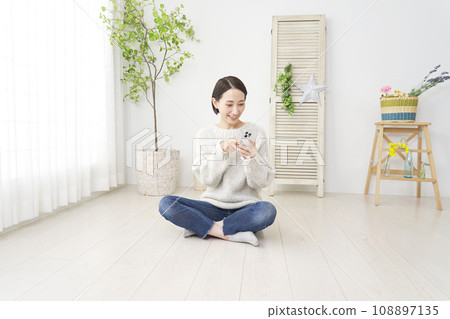 一個女人在客廳使用智慧型手機，全身 108897135