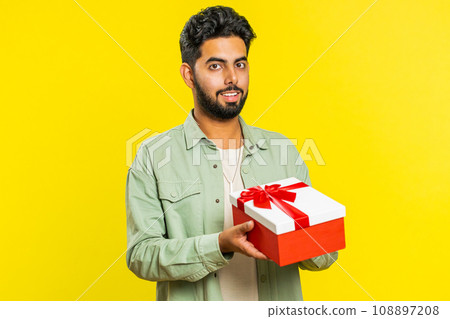 Smiling man presenting birthday gift present box stretches out hands, promotion discount sale 108897208