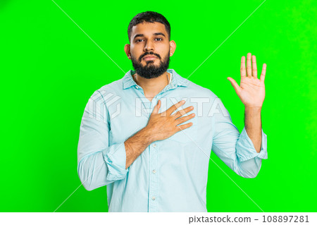 Indian man raising hand to take oath, promising to be honest and to tell truth keeping hand on chest Indian man raising hand to take oath, promising to be honest and to tell truth keeping hand on chest 108897281