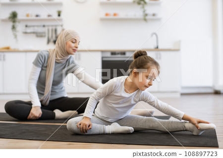 Young parent and daughter in sportswear spend time happily during workout. Young parent and daughter in sportswear spend time happily during workout. 108897723