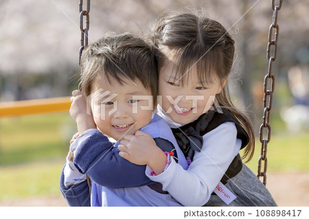 Sister and brother playing with playground equipment in the park Sister and brother playing with playground equipment in the park 108898417