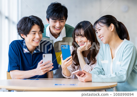 Male and female college students looking at smartphones 108899894