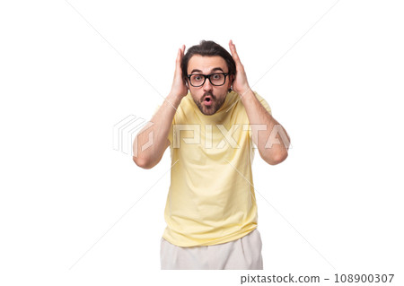 young brunette man in a t-shirt and glasses closed his ears in shock on a white background with copy young brunette man in a t-shirt and glasses closed his ears in shock on a white background with copy 108900307