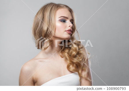 Pretty woman with makeup and long healthy blonde shiny wavy hair posing Pretty woman with makeup and long healthy blonde shiny wavy hair posing 108900793