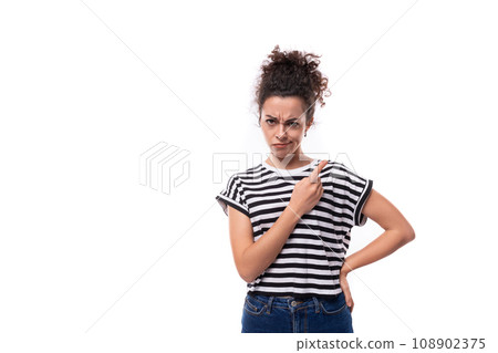 young frustrated curly brunette lady with black hair dressed in a striped t-shirt looks offended young frustrated curly brunette lady with black hair dressed in a striped t-shirt looks offended 108902375