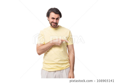 young well-groomed european brunette guy with a beard and mustache points his hand to the side 108903141
