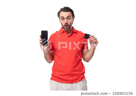 young brunette man in red t-shirt holding smartphone and credit card with mock up isolated on white 108903256