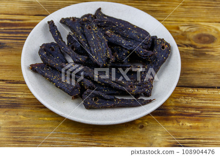 Slices of biltong (South African dried meat) on wooden table Slices of biltong (South African dried meat) on wooden table 108904476