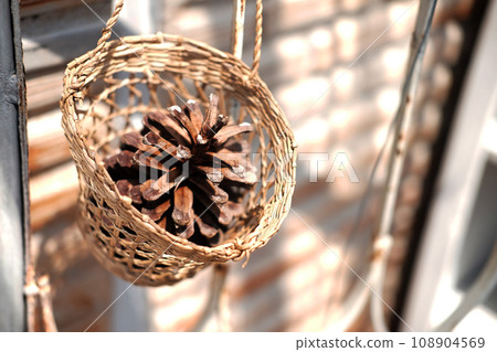 Pine cones in a woven basket is hanging on vintage wall Pine cones in a woven basket is hanging on vintage wall 108904569