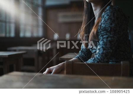 A woman sitting on a chair in an old elementary school classroom and turning around A woman sitting on a chair in an old elementary school classroom and turning around 108905425