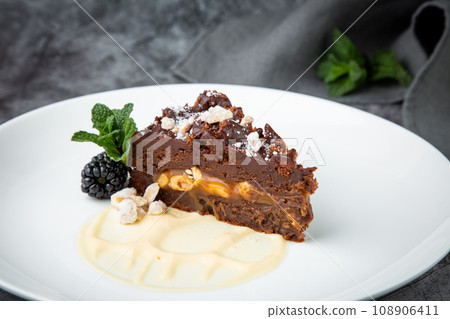 gluten free chocolate cake with nuts, berries and mint on a white plate gluten free chocolate cake with nuts, berries and mint on a white plate 108906411