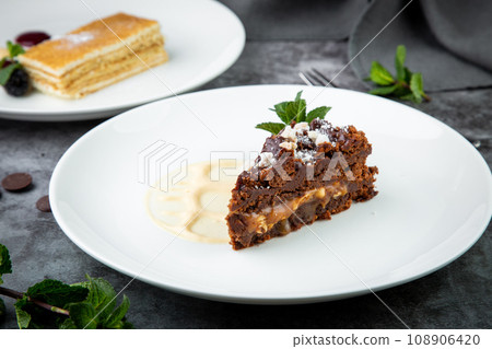 gluten free chocolate cake with nuts, berries and mint on a white plate 108906420
