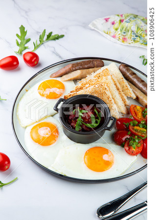 English breakfast with grilled sausages, scrambled eggs, cherry tomatoes and toast 108906425