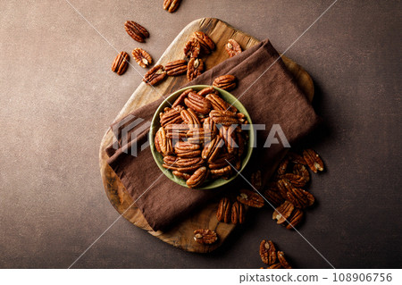 Pecan nuts in a bowl on a brown background, top view 108906756