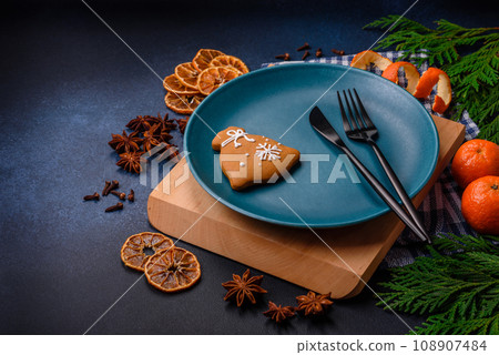 Beautiful festive Christmas composition of an empty plate, tangerine and gingerbreads Beautiful festive Christmas composition of an empty plate, tangerine and gingerbreads 108907484