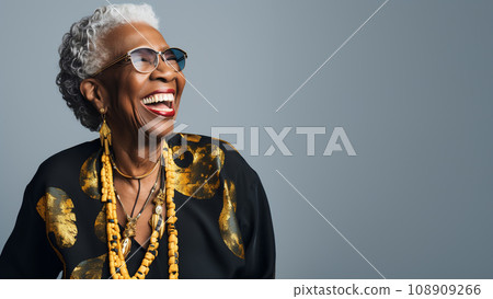 A black elderly woman laughing with glasses and necklaces against grey background 108909266