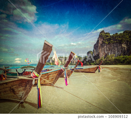 Vintage retro hipster style travel image of Long tail boats on tropical beach (Railay beach) in Thailand with grunge texture overlaid Vintage retro hipster style travel image of Long tail boats on tropical beach (Railay beach) in Thailand with grunge texture overlaid 108909312