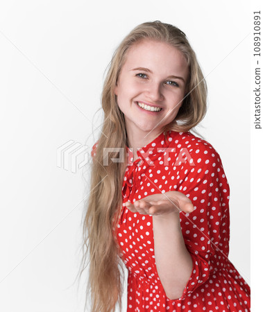Smiling blond woman stretches her one palm to camera. Portrait of model in red polka dot dress Smiling blond woman stretches her one palm to camera. Portrait of model in red polka dot dress 108910891