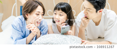 Parents and children watching smartphones in bed Parents and children watching smartphones in bed 108911287