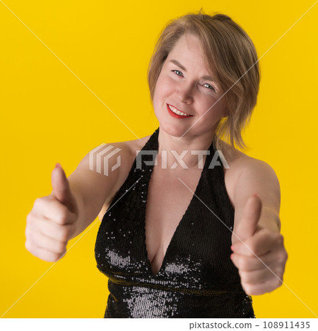 Portrait of curvy mature blonde in evening gown, giving two thumbs up and smiling with satisfaction Portrait of curvy mature blonde in evening gown, giving two thumbs up and smiling with satisfaction 108911435