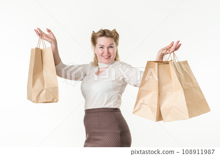 Waist up photo of happy smiling blonde woman holding shopping paper disposable bags with purchases Waist up photo of happy smiling blonde woman holding shopping paper disposable bags with purchases 108911987