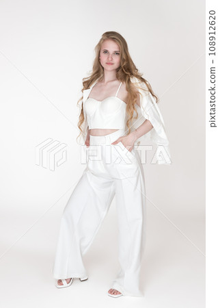 Full length fashion model holding hands in trousers pockets. Woman in suit jacket, corset top, pants Full length fashion model holding hands in trousers pockets. Woman in suit jacket, corset top, pants 108912620