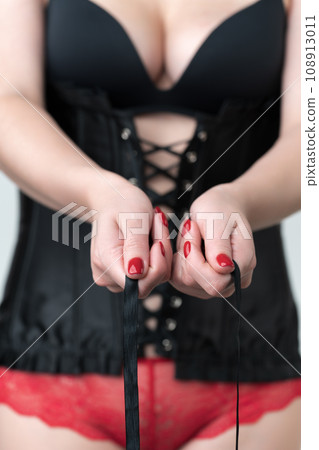 Woman hands lacing up ties on corset. Closeup female wearing lingerie - corset, brassiere, panties 108913011
